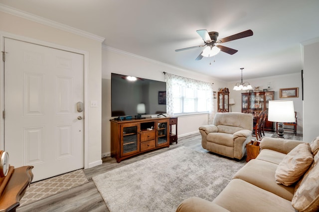 living room with ceiling fan with notable chandelier, light hardwood / wood-style floors, and crown molding