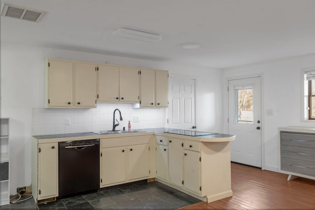 kitchen with black appliances, cream cabinetry, sink, and tasteful backsplash