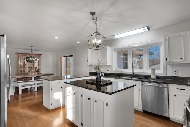 kitchen featuring appliances with stainless steel finishes, an inviting chandelier, white cabinetry, and a center island