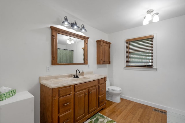 bathroom with toilet, vanity, and hardwood / wood-style flooring