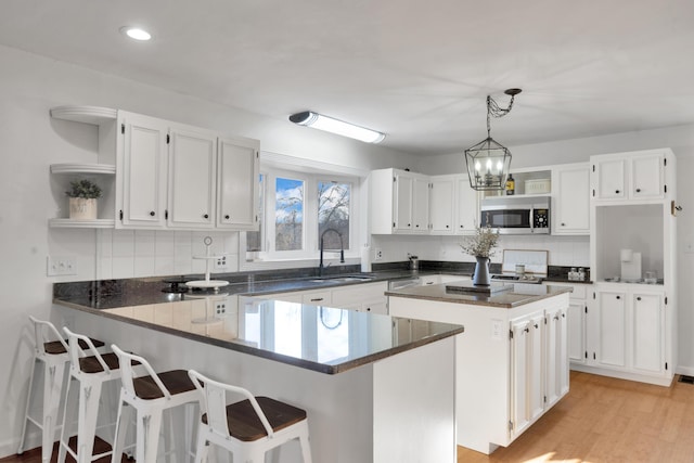 kitchen featuring sink, an inviting chandelier, white cabinetry, and a center island