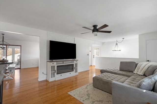 living room with ceiling fan with notable chandelier and hardwood / wood-style floors