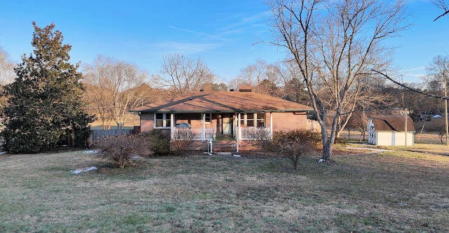 ranch-style house with covered porch, a shed, and a front lawn