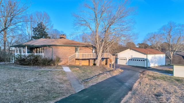 single story home with covered porch, a garage, a front yard, a wooden deck, and an outdoor structure