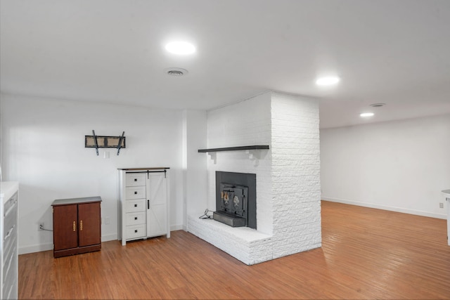 unfurnished living room featuring light hardwood / wood-style floors and a wood stove