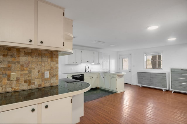 kitchen with white cabinetry, black dishwasher, tasteful backsplash, dark hardwood / wood-style floors, and kitchen peninsula