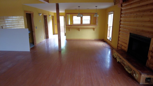 unfurnished living room with a chandelier, a fireplace, and wood-type flooring