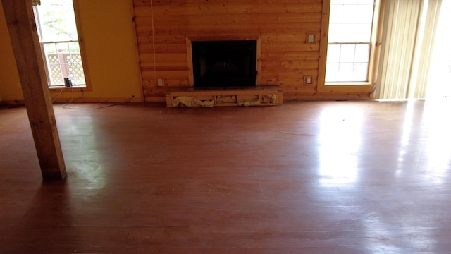 unfurnished living room featuring a stone fireplace, a wealth of natural light, and hardwood / wood-style flooring