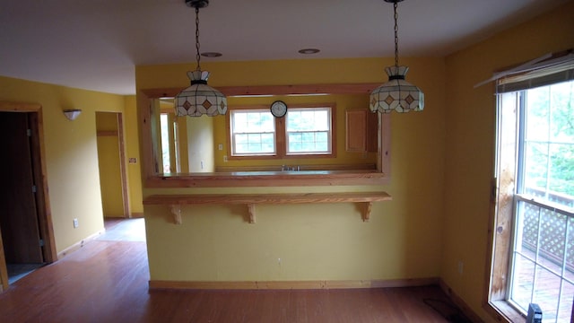 kitchen featuring a kitchen breakfast bar, kitchen peninsula, pendant lighting, and light wood-type flooring