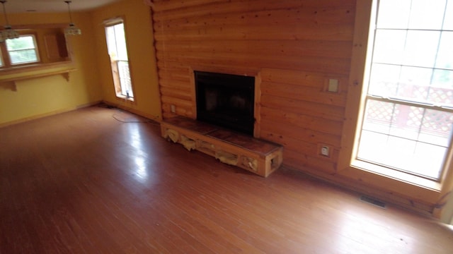 unfurnished living room with a tiled fireplace and wood-type flooring