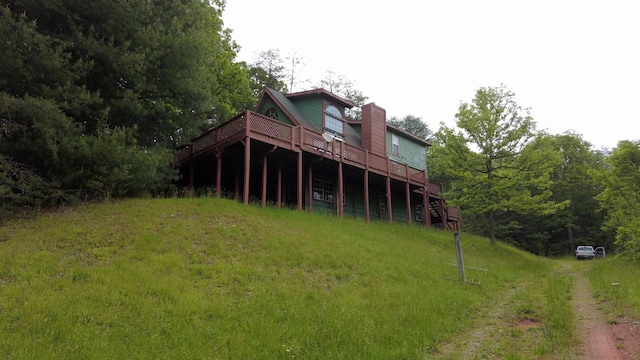 rear view of house featuring a lawn and a deck