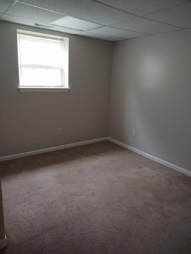 carpeted spare room featuring a paneled ceiling and baseboards