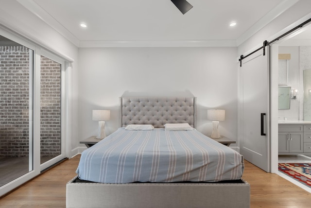 bedroom featuring access to exterior, a barn door, light hardwood / wood-style floors, and ensuite bath