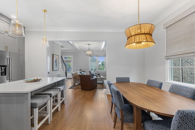 dining room featuring an inviting chandelier, ornamental molding, and hardwood / wood-style flooring