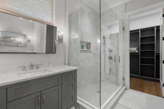 bathroom with hardwood / wood-style floors, vanity, and a shower with door