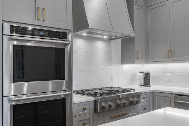 kitchen featuring custom range hood, appliances with stainless steel finishes, and gray cabinetry