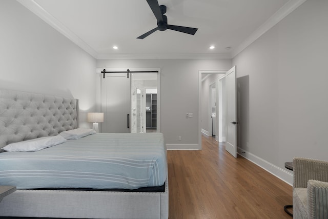 bedroom featuring hardwood / wood-style floors, a barn door, ceiling fan, and crown molding