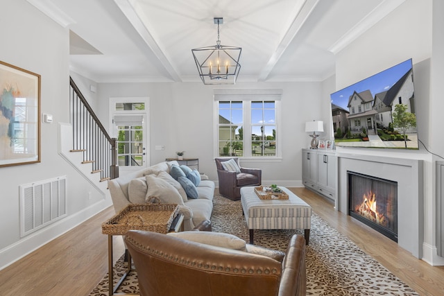 living room with a notable chandelier, beam ceiling, light wood-type flooring, and crown molding