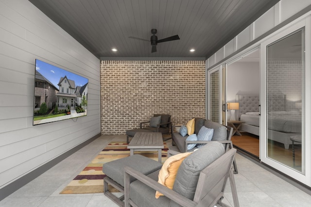 cinema room featuring ceiling fan and brick wall