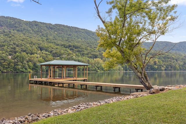 view of dock with a yard and a water and mountain view