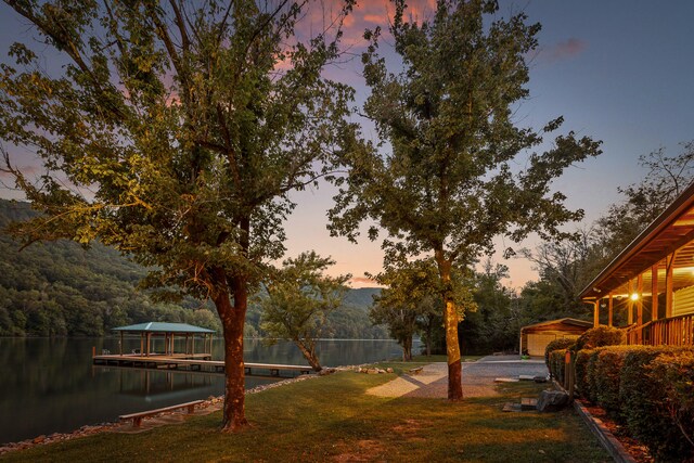 yard at dusk featuring a water view