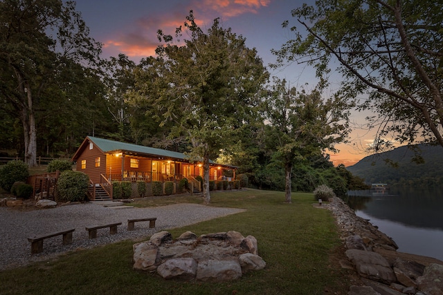 yard at dusk with a deck with water view