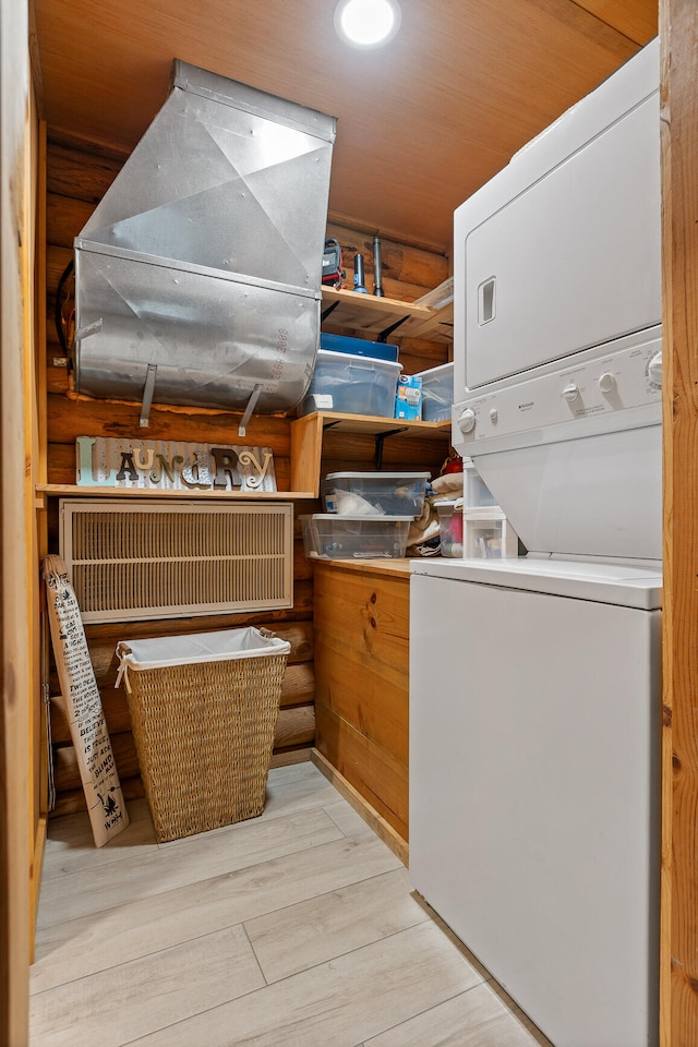 clothes washing area with light hardwood / wood-style floors, wooden ceiling, and stacked washer and clothes dryer