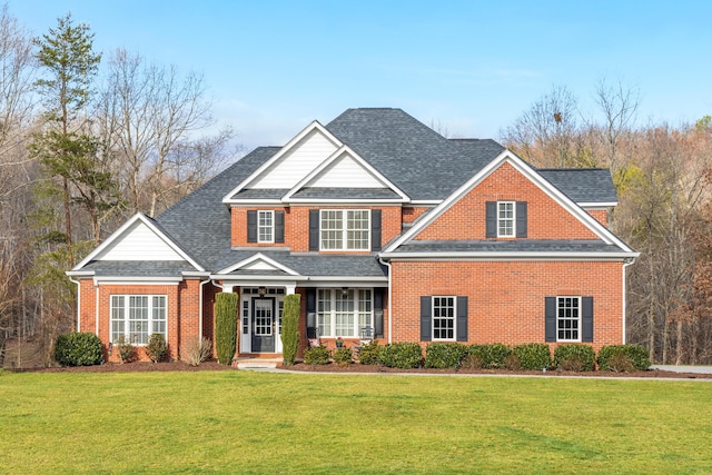 view of front of property with a front lawn, roof with shingles, and brick siding