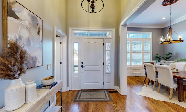 entrance foyer with hardwood / wood-style flooring, ornamental molding, and a chandelier