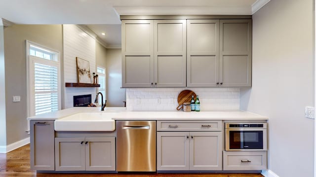 kitchen with appliances with stainless steel finishes, gray cabinetry, backsplash, crown molding, and sink