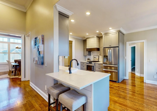 kitchen featuring gray cabinets, sink, light wood-type flooring, appliances with stainless steel finishes, and a kitchen breakfast bar