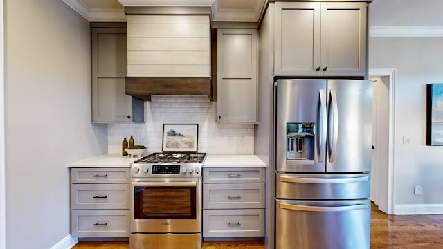 kitchen with stainless steel appliances, decorative backsplash, ornamental molding, hardwood / wood-style flooring, and gray cabinetry