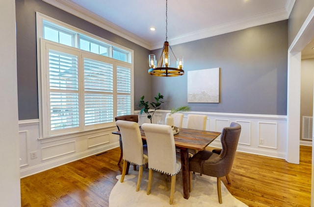 dining area with hardwood / wood-style floors, crown molding, and a notable chandelier