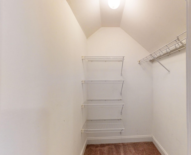 spacious closet featuring vaulted ceiling and dark carpet