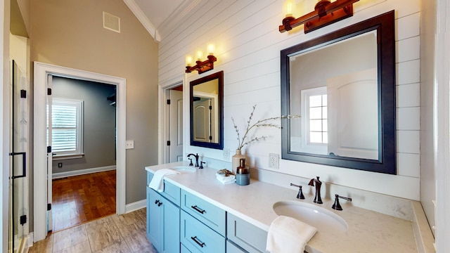 bathroom featuring vaulted ceiling, ornamental molding, hardwood / wood-style floors, and vanity