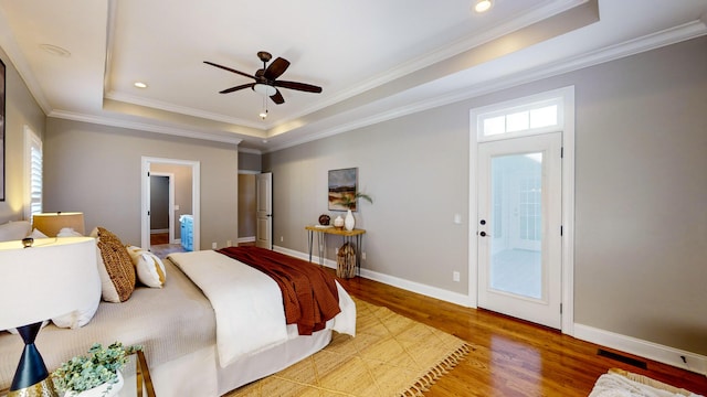 bedroom with ceiling fan, crown molding, light hardwood / wood-style flooring, and a tray ceiling