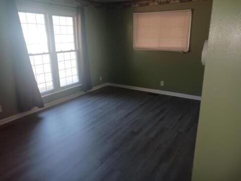 empty room with a wealth of natural light and dark hardwood / wood-style floors