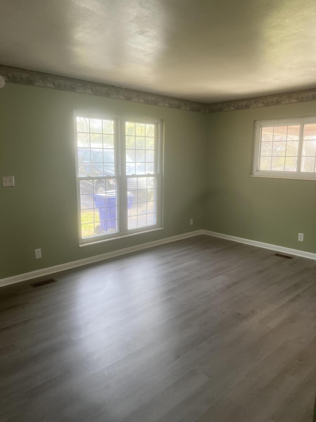 unfurnished room with dark wood finished floors, baseboards, and visible vents
