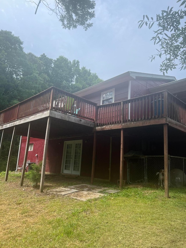 rear view of property featuring a lawn, a wooden deck, and french doors