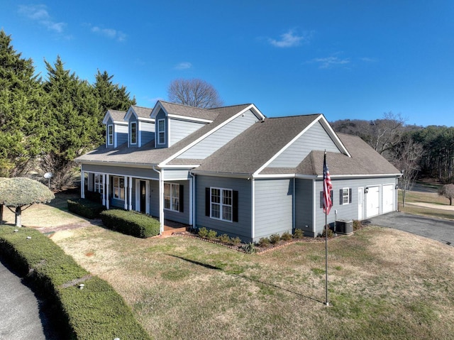 view of front of home with a porch, a garage, central air condition unit, and a front lawn