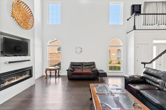 6706 Willow Trace Dr, Chattanooga, TN 37421 - living area featuring a towering ceiling, dark wood-style flooring, a glass covered fireplace, and baseboards