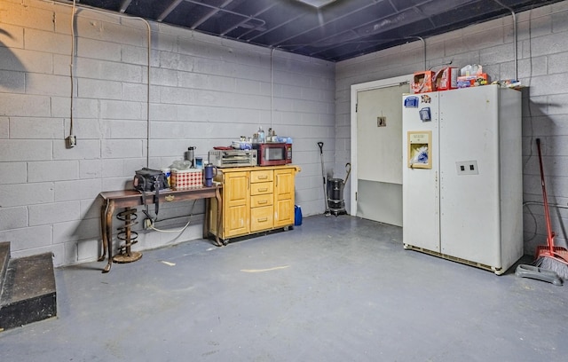 garage featuring concrete block wall and freestanding refrigerator