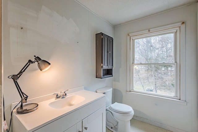 bathroom featuring a healthy amount of sunlight, vanity, toilet, and a textured ceiling