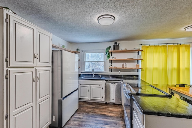 kitchen featuring appliances with stainless steel finishes, dark countertops, a sink, and open shelves