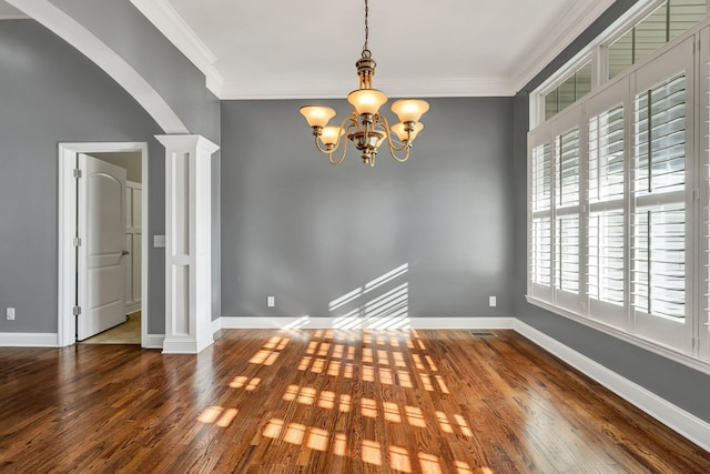 unfurnished room featuring decorative columns, wood-type flooring, a chandelier, and ornamental molding