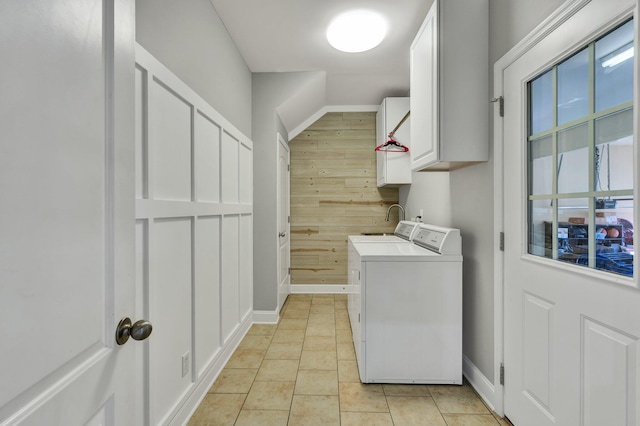 washroom with sink, cabinets, wood walls, washer and clothes dryer, and light tile patterned flooring