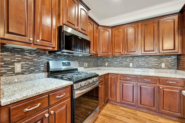 kitchen with light stone countertops, light wood-type flooring, backsplash, stainless steel appliances, and crown molding