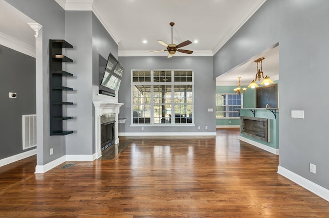 unfurnished living room with ceiling fan with notable chandelier, dark hardwood / wood-style floors, and ornamental molding