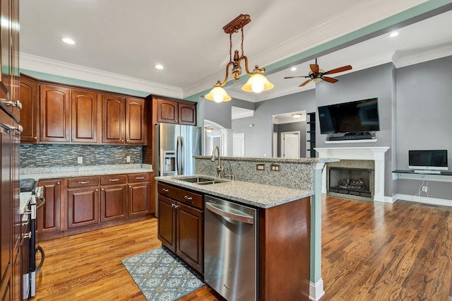 kitchen with a kitchen island with sink, sink, light wood-type flooring, and appliances with stainless steel finishes