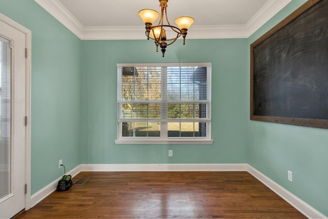 empty room featuring a chandelier, wood-type flooring, and crown molding